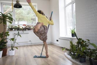 A girl dances with a mop to clean the floor in a new house, general cleaning in an empty room, the
