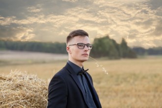 Young man with glasses thinking and standing on the field, vintage instagram toning