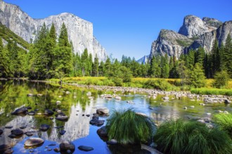 Picturesque El Capitan and mountain peaks are reflected in the smooth water of the Merced River.