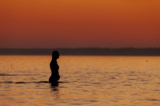 A woman cools down in a fresh water lake at the end of hot summers day