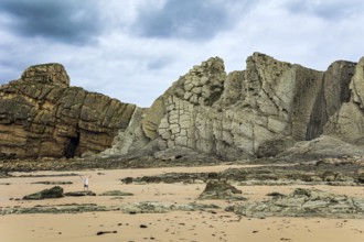 Noon on the beach of Playa di Arnia, Spain. Man admiring the magnificent scenery. Cantabria. Windy