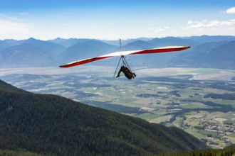 Long shot of flying extremal hang glider. Young man enjoying his recreational journey to Creston,
