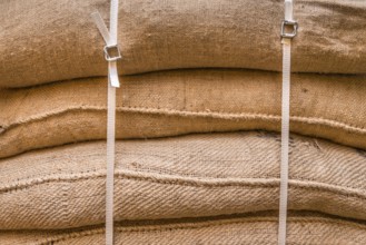 Close-up image of jute sacks filled with goods, piled upon each other and tied up, ready for