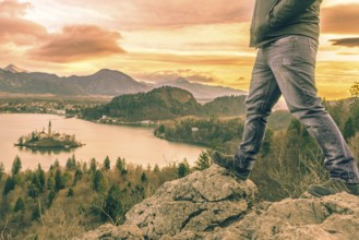 Man equipped with hiking shoes climbed on rocks above the lake Bled from Slovenia, in a December