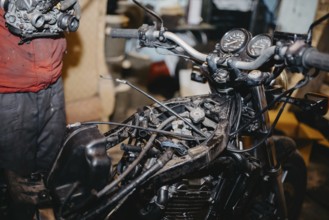 Mechanic repairing motorcycle in a workshop, focusing on engine and gauges