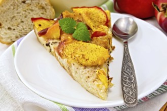 Sweet bread pudding of peaches with milk and eggs, a spoon in a plate on a linen towel, milk in