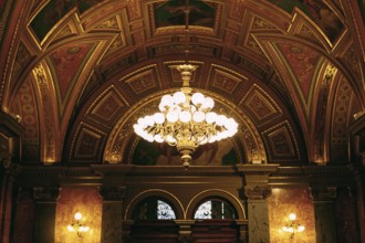 Large golden chandelier under the gilded ceiling in the interior.