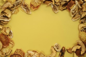 Oval ornament made of thin slices of dried fruits on a yellow background.
