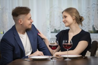 The girl strokes her partner's shoulder. The couple is sitting close together at a table. Two