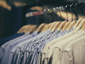 Close up view of man clothes hang in clothes store. Hangers with different male clothes. Copy space