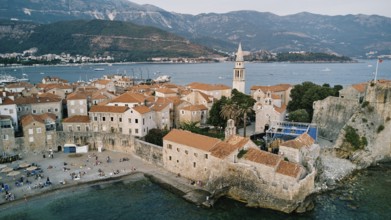 Stone fortress walls of the old town near the high bell tower. Budva, Montenegro. Drone.
