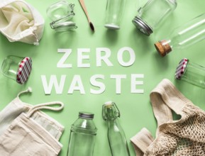 Zero waste concept. Textile eco bags, glass jars and bamboo toothbrush on green background with