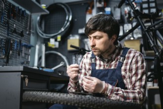 Bicycle mechanic fixing cycle wheel in repair shop. Velocipede service. Repairer male bike shop