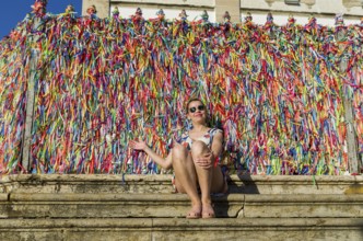 Young Woman in front of the grid with colored ribbons of Bonfim church in Salvador Bahia Brazil