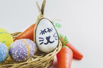 Happy easter bunny egg and eggs colored eggs in a basket isolated on a trendy white background.