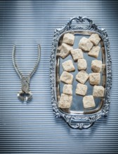 Vintage sugar cubes pliers tray on striped background