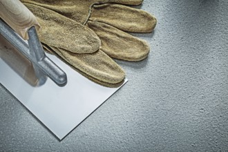 Stainless bricklaying trowel leather protective glove on concrete background construction concept