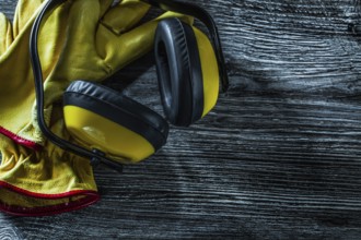 Protective earmuffs leather gloves on wooden board