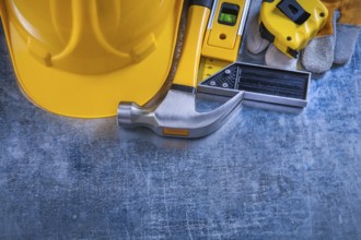Safety gloves try square construction level tape-line hard hat and claw hammer on metallic