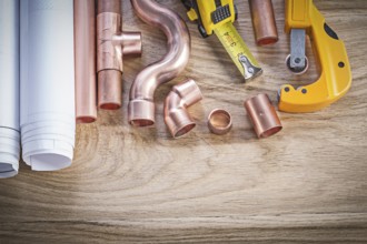 Construction plans tape line water pipe cutter fixtures on wooden board plumbing concept