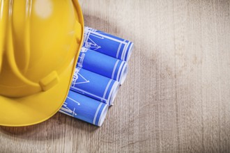Wooden board with blue rolled up construction drawings building helmet