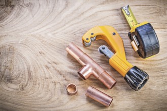 Copper water pipe cutter fittings tape measure on wood board top view plumbing brassware concept