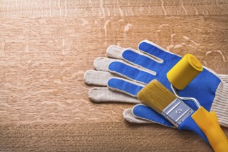 Protective gloves paint roller and brush on wooden board construction concept