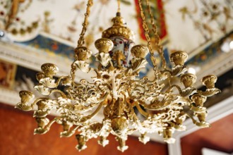 Close-up of an antique gold Italian chandelier. A chandelier-chandelier on gilded chains hangs