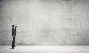 Businessman in empty concrete room drawing on wall