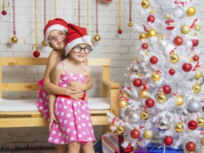Two funny sisters four girls and six years of playing and having fun in the home New Years interior
