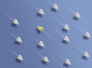 group of paper planes flying in one direction on blue background and one paper glider going in