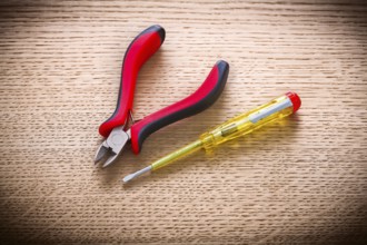 Electrical tester and pliers on wooden board