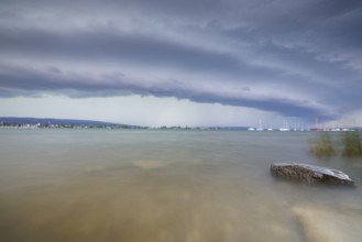 Gloomy mood with boats on the horizon under a cloudy, grey sky with a shelf cloud, Allensbach,