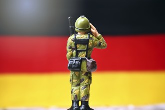 Soldier in front of a German flag, symbolic photo of compulsory military service