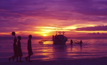 Philippines: Three local football boys walking on the beach on the island of Boracay