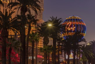 A picture of the Paris Las Vegas Balloon Sign and the nearby palm trees at sunset