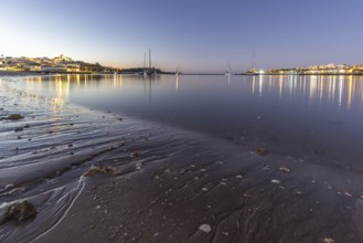 Night shot of a sandy beach and harbour at low tide. Panoramic image of an illuminated historic