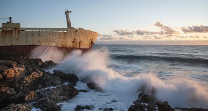 Abandoned ship in the stormy sea with big wind waves during sunset