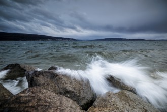 Sprayed waves crash against stones in front of a cloudy sky, harbour, Mittelzell, Reichenau, Lake