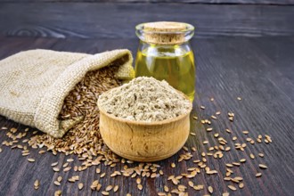 Flax flour in a bowl, seeds in a bag and on a table, linseed oil in a glass jar on a wooden board