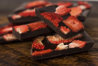 Stack of chocolate slices with strawberry on wooden background