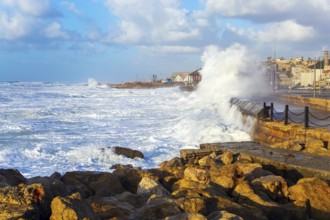 Huge stones protect the coast from huge storm waves. Powerful winter surf takes off with snow-white