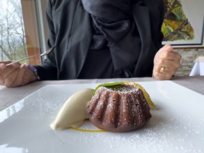 Woman Eating on a White Plate With an Elegant Warm Dark Chocolate Cake Dessert With Vanilla Ice