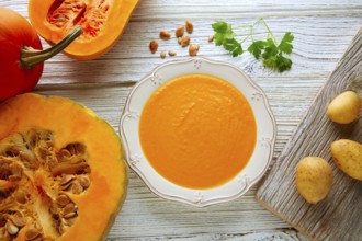 Pumpkin soup cream on a wooden table and ingredients