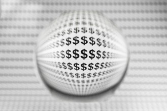 Studio shot of a glass sphere on a sheet of paper with dollar signs
