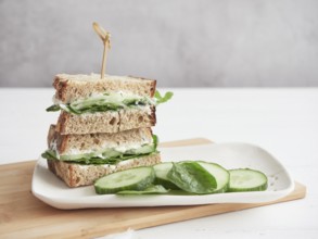 Cucumber and green spinach sandwich, cut in half and stacked on white platter