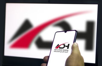Alpha Dhabi Holding (ADH) logo on smartphone.