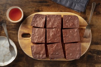 Chocolate brownie with tea, simple coffee cake, overhead flat lay view on a dark rustic wooden