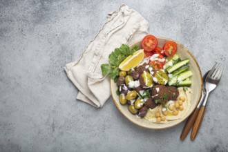 Falafel salad bowl with hummus, vegetables, olives, herbs and yogurt sauce. Vegan lunch plate top