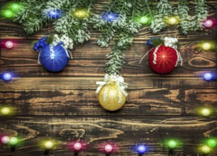 Balls and garland at fir branch on wooden background